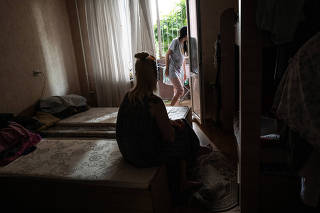 Natasha, back to camera, speaks with her daughter on Aug. 18, 2022, in the apartment they share in Kyiv, after fleeing their home in Lyman, in eastern Ukraine. (Lynsey Addario/The New York Times)