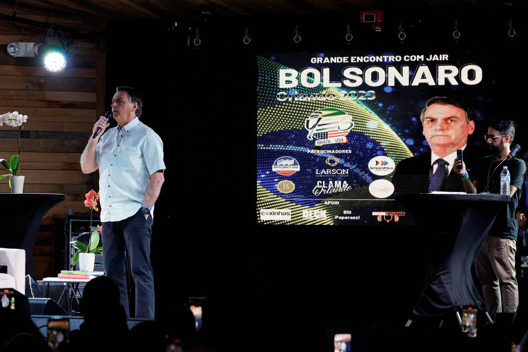 Ex-presidente fala ao microfone e o telão mostra foto dele com os dizeres "grande encontro com Bolsonaro"