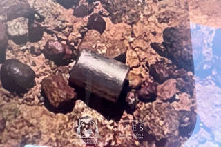A view shows a radioactive capsule lying on the ground, near Newman