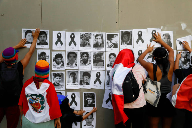 Manifestantes colam fotos na parede durante protesto em Lima