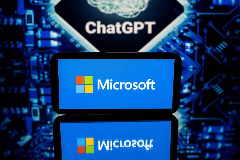 Notebook com logo da Microsoft na tela, à frente de banner do ChatGPT. Foto foi tirada em evento de tecnologia realizado em Toulouse, na França