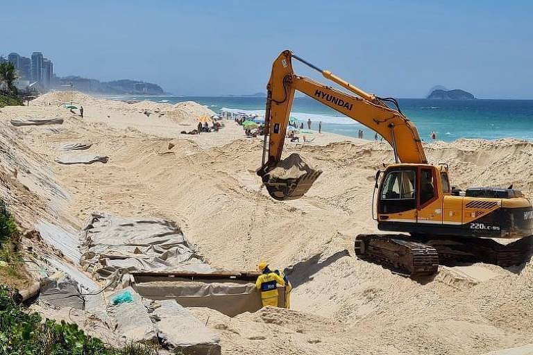 Retroescavadeira retira areia da praia da Barra de um grande buraco aberto pela obra