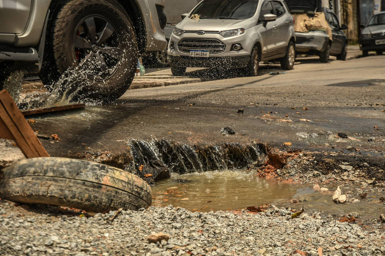 Buracos e bueiro com esgoto transbordando no asfalto recém-recapeado na rua Morubixaba, em Cidade Lider, na zona leste de São Paulo; região teve salto de 39% nos pedidos de tapa-buraco