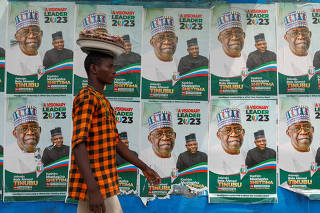 A man walks past electoral campaign posters displayed at a bus stop, ahead of Nigeria's Presidential elections, in Lagos