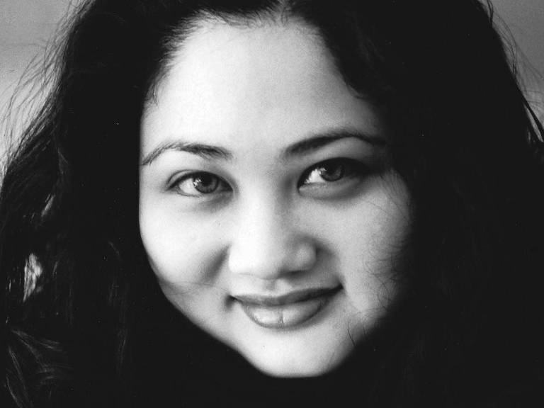 mulher de traços orientais sorri em foto em preto e branco