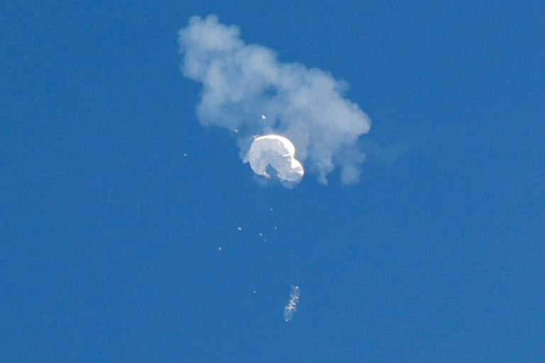 Uma linha de fumaça brança é vista em um céu azul; é a vista do balão chinês abatido no céu dos Estados Unidos
