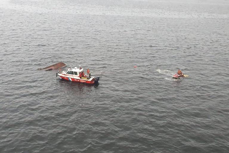 Uma lancha e um jet ski nas águas da baía de Guanabara perto de uma embarcação naufragada apenas com a proa sem estar submersa