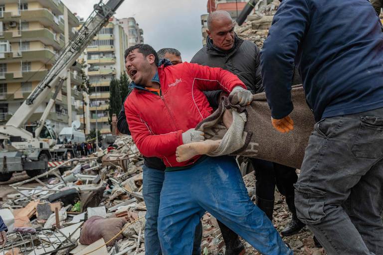 Socorrista carrega corpo de vítima encontrado em meio a destroços de prédios na cidade turca de Adana