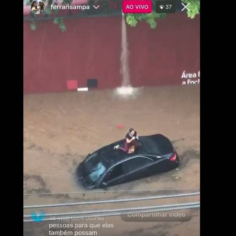 Mulher sobe no teto do carro para fugir da enchente em frente ao estádio do Morumbi, devido ao temporal que atingiu a cidade de São Paulo na tarde desta terça-feira (7