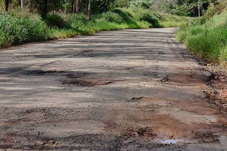 A foto mostra trecho da rodovia MG-353, que liga Guarani a Rio Novo, em Minas Gerais, com grande número de buracos e sem sinalização.