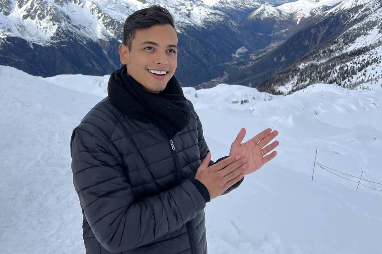 Homem jovem, 22, agasalhado entre montanhas nevadas