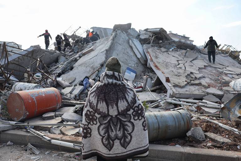 Homem observa missão de resgate em ruínas de prédios destruídos por terremoto na Turquia