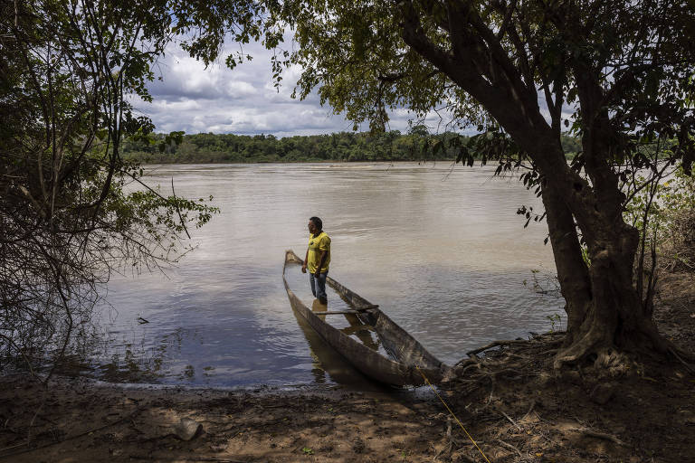 Alexandre Apolinário, 38, coordenador de um grupo de monitoramento da Terra Indígena Boqueirão, em Roraima, observa embarcação com garimpeiros passar pelo rio Uraricoera 