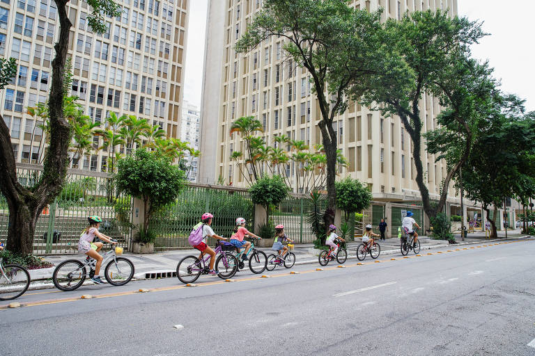 Estudantes em bicicletas passam em fila por ciclovia
