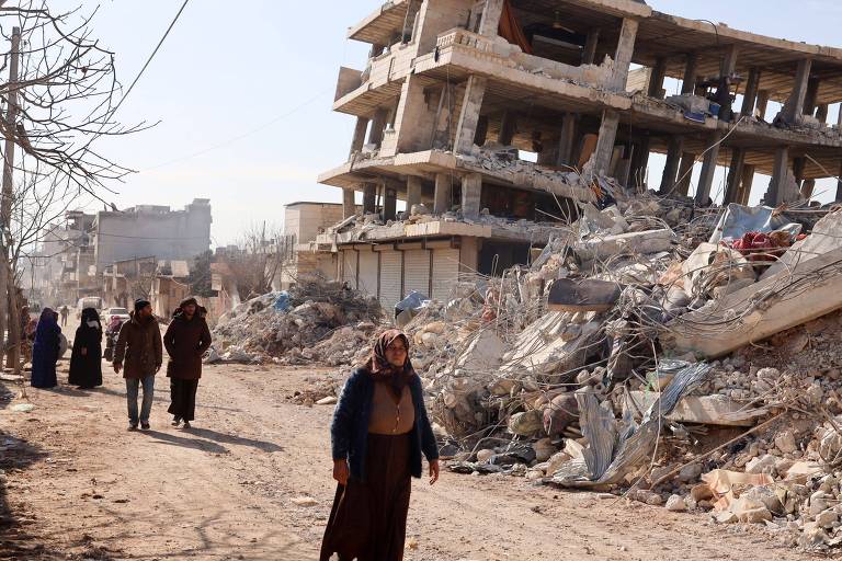 Moradores caminham entre prédios destruídos na cidade de Jandaris, na parte controlada pelos rebeldes da província de Aleppo, na Síria