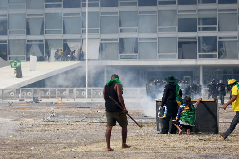 Um homem carrega um bastão de ferro durante ataques às sedes dos três Poderes