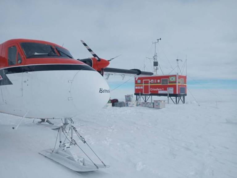 Avião pousado no gelo em primeiro plano com o módulo ao fundo