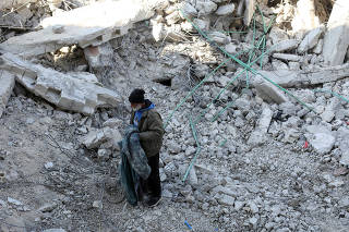 Syrian father Nader Fadil stands on the rubble of his damaged home, in Jableh