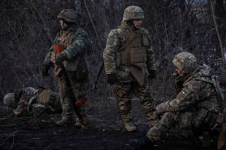 Ukrainian servicemen rest on a road outside the frontline town of Bakhmut