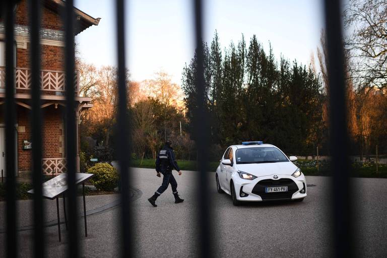 Policial caminha em direção a viatura no parque Buttes-Chaumont, em Paris, após restos de corpo de mulher serem encontrados