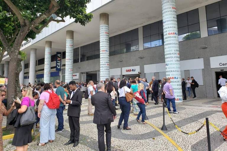 Imagem colorida mostra dezenas de pessoas na calçada do prédio da OAB-RJ após evacuação por ameaça de bomba no edifício