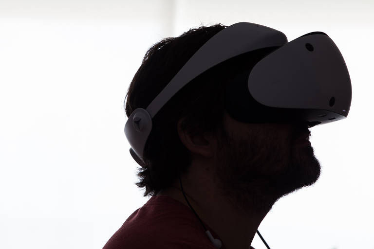 Homem com headset do PlayStation VR2 contra a luz, em frente a fundo branco