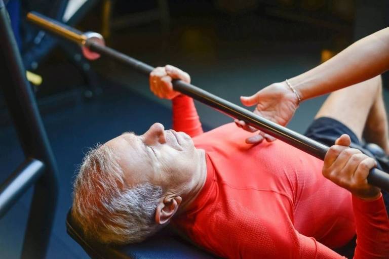 Homem de meia-idade faz musculação em uma academia