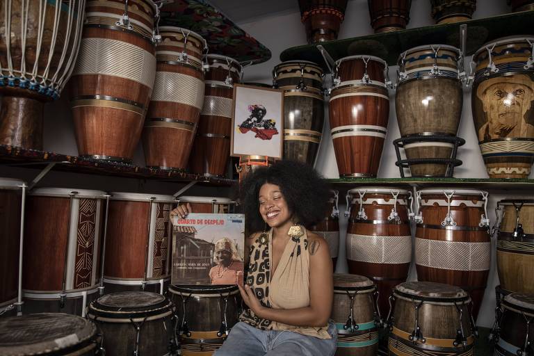 Em foto colorida a percussionista Sthe Araujo aparece segurando o LP 'Quarto de Despejo', de  Carolina Maria de Jesus