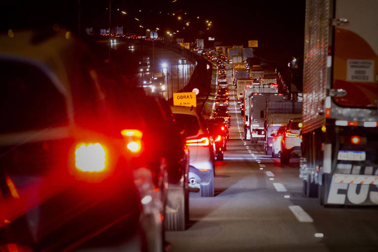 Carros trafegam em rodovia durante a noite