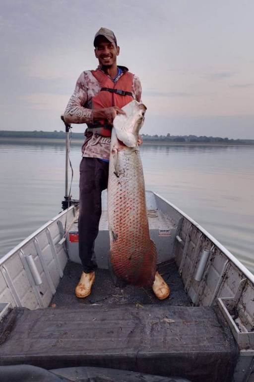 Foto de homem segurando peixe de grande porte