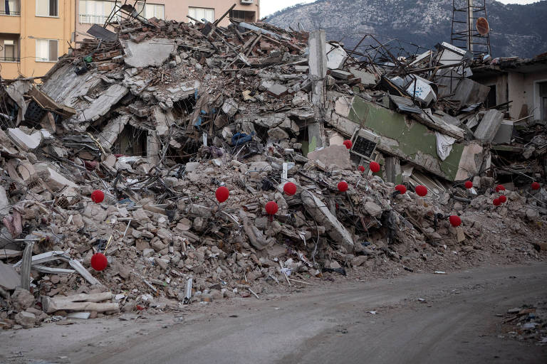 Balões vermelhos são colocados em homenagem às vítimas em ruínas de edifício destruído em Antáquia, na Turquia