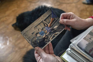 Liudmyla Shestakova holds a childhood photo of her son Taras Melster and Olha, whom he married when they grew up, in Kropyvnytskyi, Ukraine, Feb. 12, 2023. (Ivor Prickett/The New York Times)