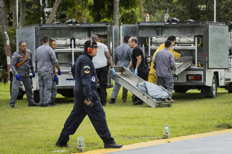 Corpos de vítimas são colocados em veículos da Polícia Científica 