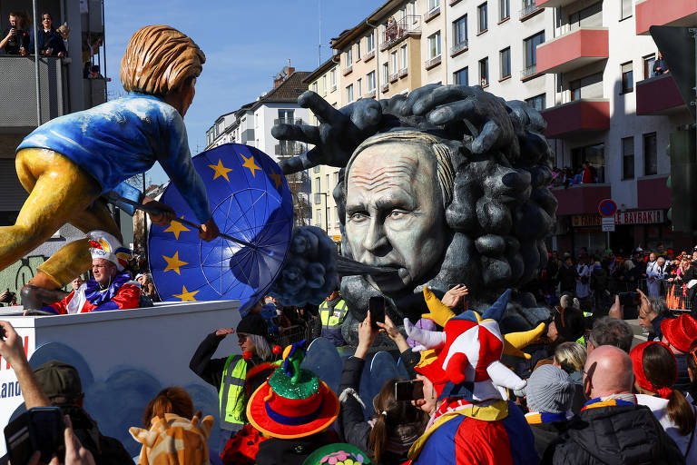 Neste carro alegórico em Mainz, a presidente da Comissão Europeia, Ursula von der Leyen, abre um guarda-chuva com a bandeira da União Europeia 'para se proteger' de Putin