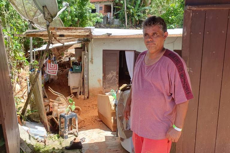 O vendedor Lício Mota da Silva, 45, em frente à casa parcialmente destruída; ele permaneceu na sala de casa quando a terra desmoronou