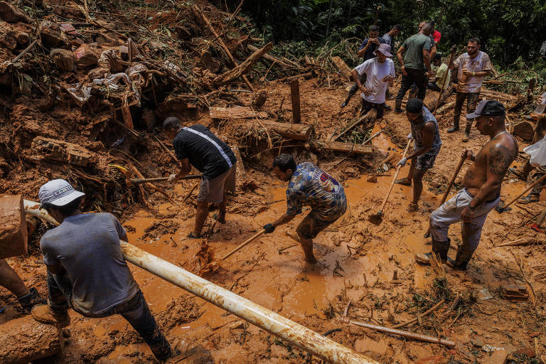 Bombeiros e voluntários trabalham em meio à lama em busca de vítimas dos deslizamentos na Barra do Sahy, em São Sebastião