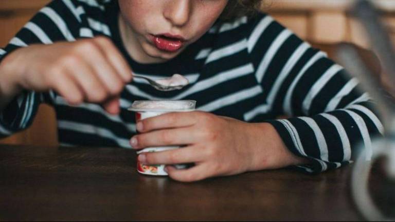 Criança tomando iogurte com uma colher