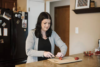 Heather Rendulic, who had a stroke at age 23, disabling her left arm and hand and making tasks like tying shoes impossible, cuts a strawberry at her home in Pittsburgh, Feb. 17, 2023. (Kristian Thacker/The New York Times)