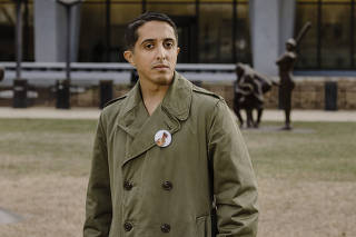 Ibrahim Almadi with a pinback-button showing his father Saadi, outside the State Department in Washington, Feb. 12, 2023. (Jason Andrew/The New York Times)