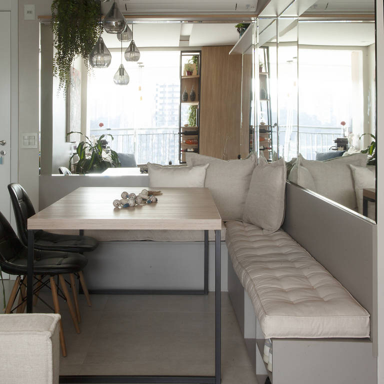 Mesa de jantar retangular com banco encostado em duas paredes perpendiculares e do outro lado, duas cadeiras