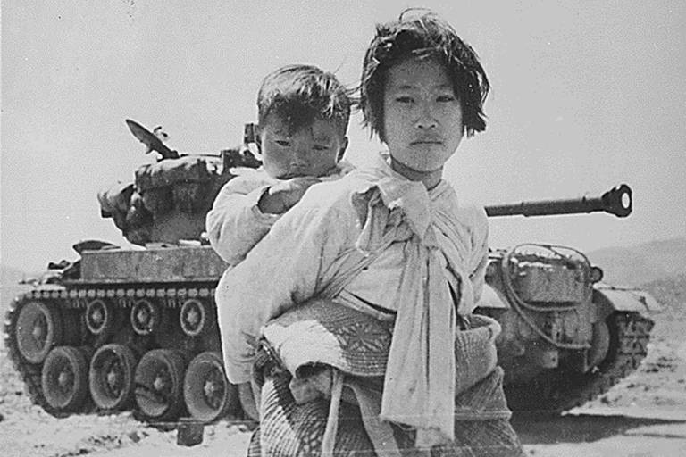 Crianças passam em frente a tanque na cidade de Haengiu, durante a Guerra da Coreia (1950-53)
