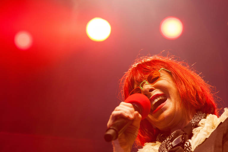 Mulher de cabelos vermelhos segura um microfone