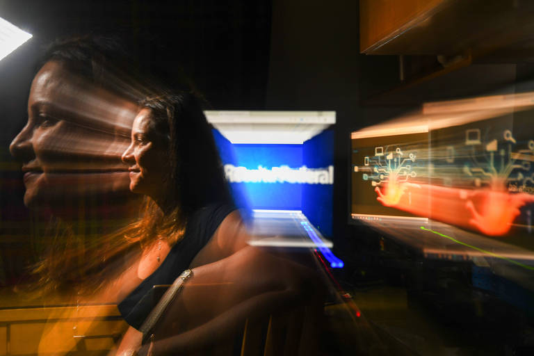 Imagem colorida mostra a servidora Tânia, de 48 anos, de perfil, entre reflexo da luz do computador