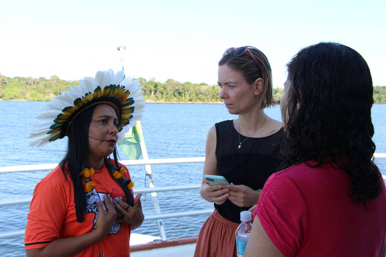 Grupo de 3 mulheres conversando em um barco com o rio ao fundo