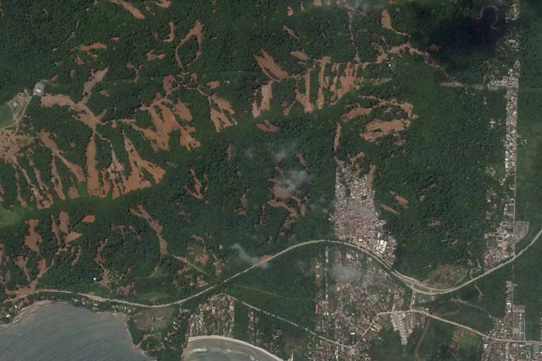 foto de satélite mostra cidade com aglomerado de casas e áreas com lama à vista, onde houve deslizamento