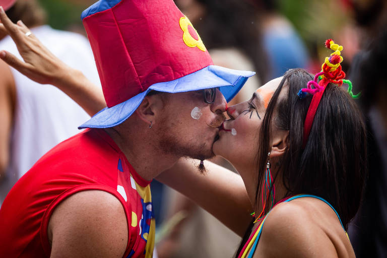 Homem e mulher se beijam. Eles estão com fantasias.