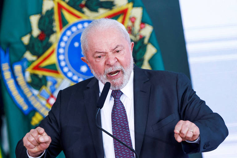 Lula, de terno e gravata escuros, discursa em frente a brasão da república
