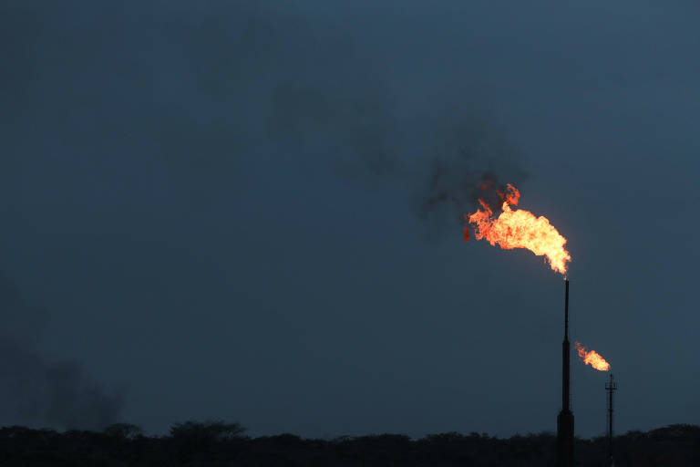 Chaminés de petroleira mexicana soltam enormes labaredas alaranjadas, que reluzem contra céu noturno