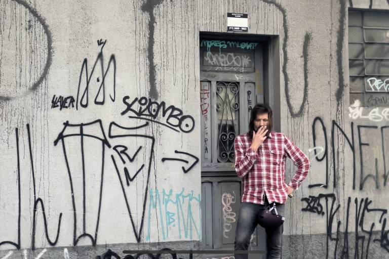 Evan Dando, vocalista dos Lemonheads, usando uma camisa xadrez e fumando um cigarro