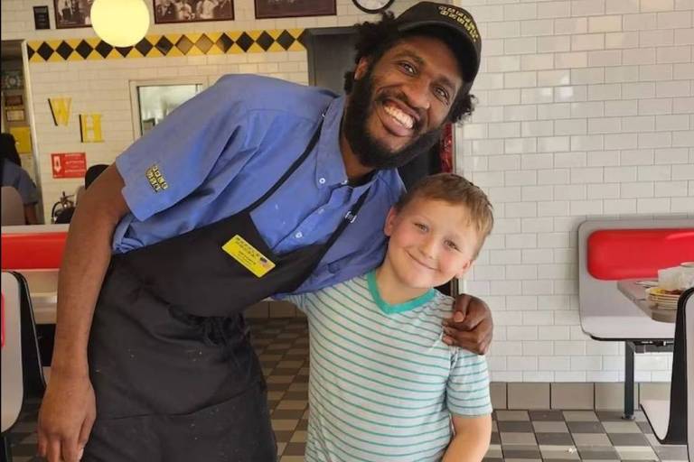 Em foto colorida, garçom negro abraça menino que o ajudou com uma vaquinha virtual